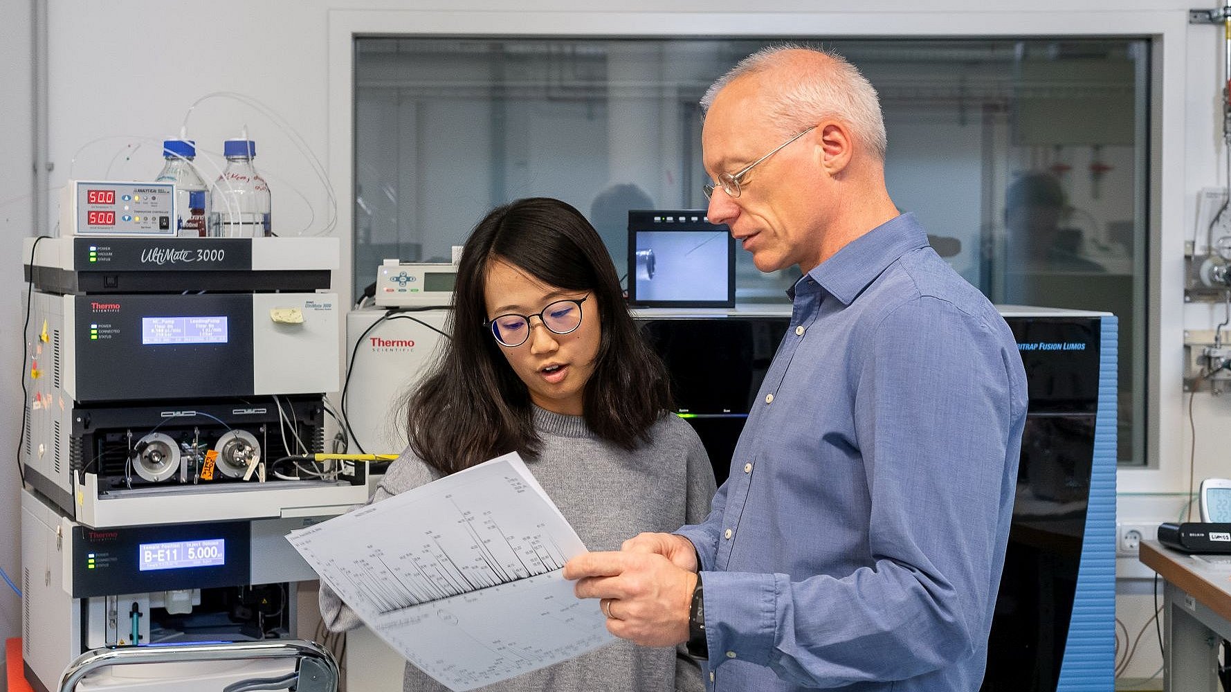 Mass spectrometers generate data at high speed, which is automatically evaluated by computers. Individual results are randomly checked for quality and significance. Prof. Küster and a colleague evaluate the results of a data collection.